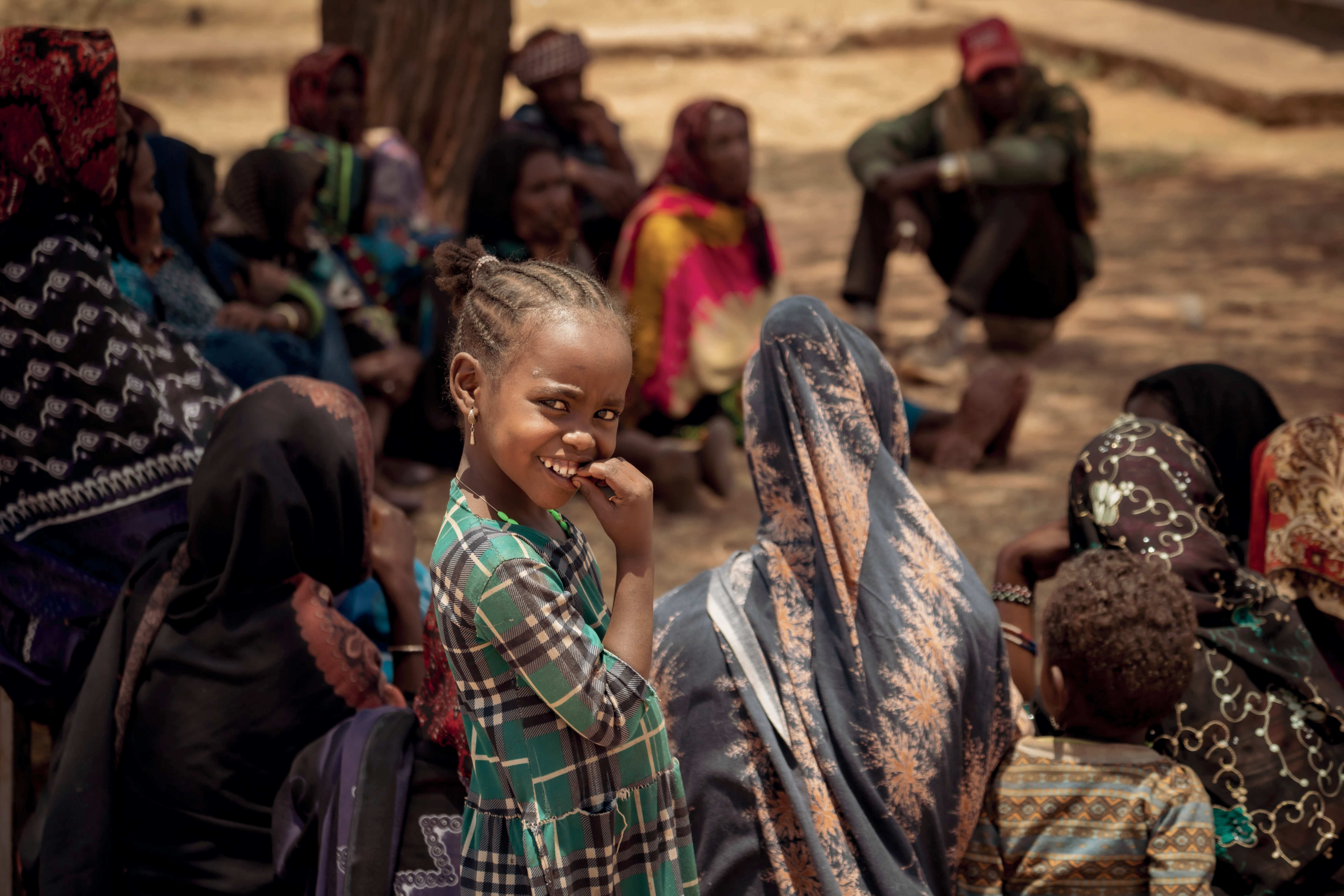 A girl in a group of women and children smiles towards the camera (source: Jakob Studnar)