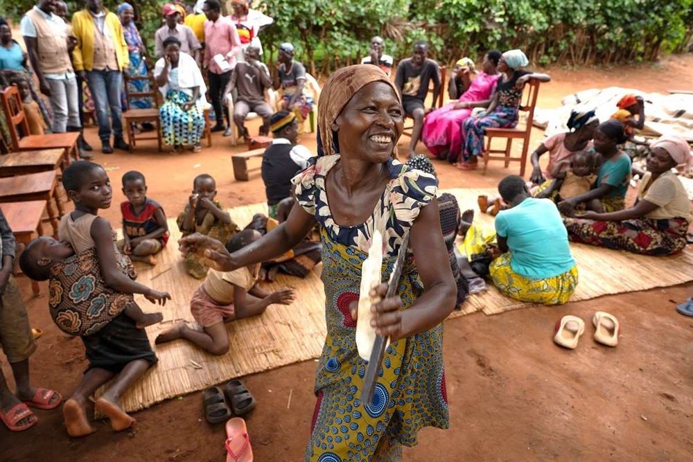 Children and Women sit on chairs and on the floor. A women in the foreground laughs (Source: Christian Nusch)