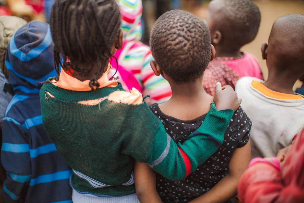 A group of childre from behind. One girl has put her arm around another. Her shirt is torn (source: Lars Heidrich) A group of childre from behind. One girl has put her arm around another. Her shirt is torn (source: Lars Heidrich)