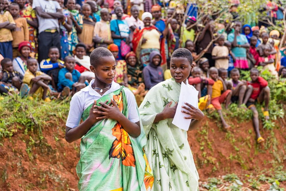 Zwei Mädchen bei einer Darbietung. Eine Kindergruppe im Hintergrund (Quelle: Martin Bondzio) Two girls performing. A group of children in the background. (Source: Martin Bondzio)