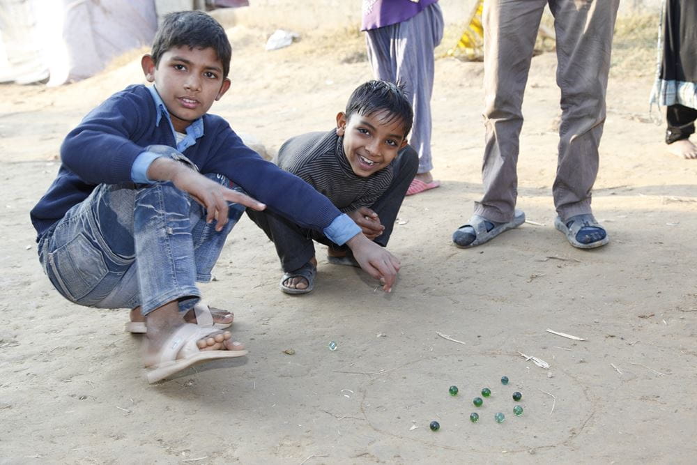 Two boys play with marbles on the floor (Quelle: Christian Herrmanny)
